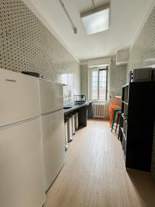 ミラノにあるBovisa Urban Gardenの白い家電製品が備わるウッドフロアの広いキッチン