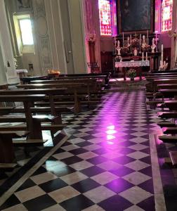 an empty church with benches and purple lights on the floor at Le Lampade di Brienno Apartment in Brienno