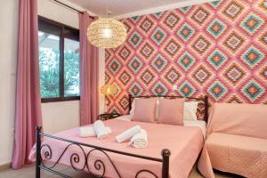 Un dormitorio con una cama rosa con toallas. en Ostria Hotel, en Skala Potamias