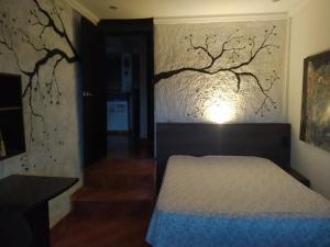 ein Schlafzimmer mit einem Bett und einem Baumgemälde an der Wand in der Unterkunft Apto Tipo Cabaña Cerca aeropuerto (PEI) in Pereira