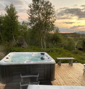a hot tub sitting on a deck with a bench at Cozy family friendly cabin at beautiful location! in Geilo
