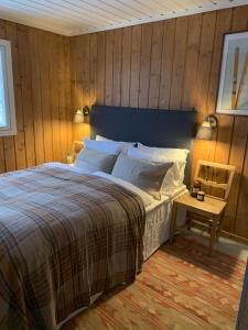 a bedroom with a bed and a wooden wall at Cozy family friendly cabin at beautiful location! in Geilo