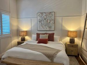 a bedroom with a large bed with two lamps at Bamboo Beach House & Studio in Byron Bay