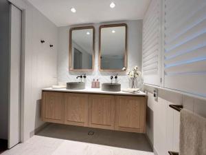 a bathroom with two sinks and two mirrors at Bamboo Beach House & Studio in Byron Bay +8 photos
