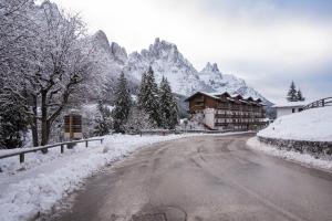 a snow covered road in front of a mountain at Hotel Colfosco in San Martino di Castrozza
