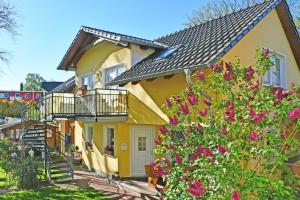 żółty dom z balkonami i kwiatami w obiekcie Ferienwohnungen Familie Dinda w mieście Baabe