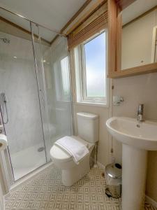 a bathroom with a toilet and a shower and a sink at Serena Holiday Caravan in Bassenthwaite
