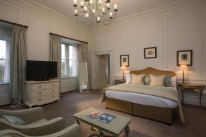 1 dormitorio con 1 cama, TV y lámpara de araña en Fawsley Hall Hotel, en Daventry