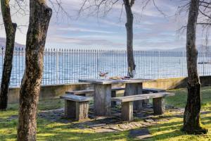 a picnic table with benches in front of the water at Villa Lago Maggiore in Lesa