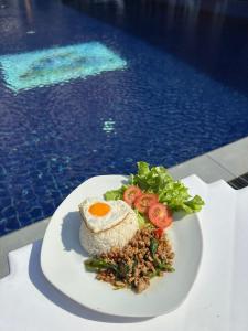 a white plate of food with an egg on top at Paradise Land Resort in Pattaya North