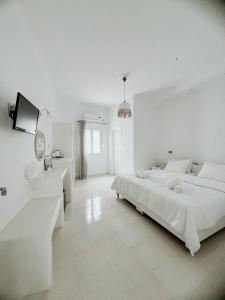 ein weißes Schlafzimmer mit einem großen Bett und einem Fernseher in der Unterkunft Hotel Thirasia in Fira