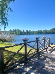 uma cerca de madeira com flores ao lado de um lago em Kaffestugan em Hällefors