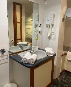 y baño con lavabo y espejo. en Grand Hôtel De Calvi, en Calvi