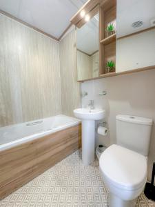 a bathroom with a toilet and a sink and a tub at Serena Holiday Caravan in Bassenthwaite