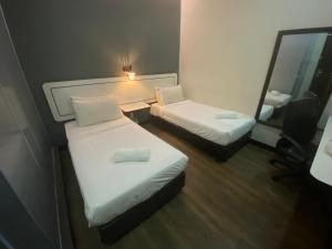 Habitación pequeña con 2 camas y espejo. en Swing & Pillows - NueVo Boutique Hotel Kota Kemuning en Shah Alam