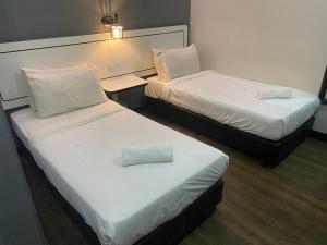 2 camas en una habitación de hotel con una almohada en Swing & Pillows - NueVo Boutique Hotel Kota Kemuning en Shah Alam