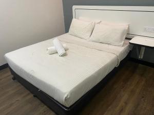 Una cama con sábanas blancas y almohadas. en Swing & Pillows - NueVo Boutique Hotel Kota Kemuning en Shah Alam