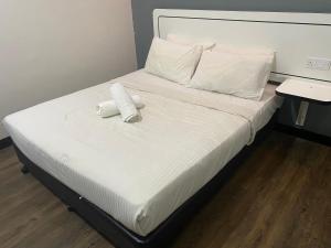 Swing & Pillows - NueVo Boutique Hotel Kota Kemuning في شاه عالم: سرير مع منشفتين ملتويتين عليه