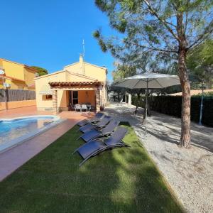 una fila de tumbonas y una sombrilla junto a una piscina en AME447 Chalet con piscina privada 9x5m y jardín vallado, en Les tres Cales