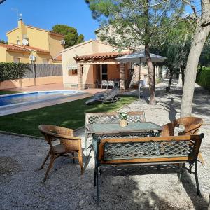 un patio con mesa, 2 sillas y sombrilla en AME447 Chalet con piscina privada 9x5m y jardín vallado, en Les tres Cales