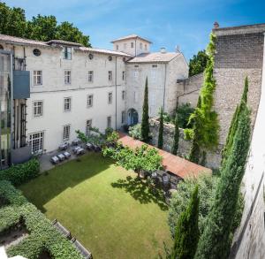 a large building with a large lawn and trees at Hôtel Cloitre Saint Louis Avignon in Avignon