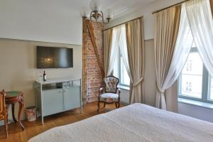 a bedroom with a bed and a chair and windows at Antonius Hotel in Tartu