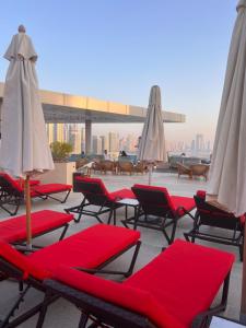 eine Gruppe von Stühlen und Sonnenschirmen auf einem Dach in der Unterkunft Serenity Suites studio in Seven Palm corner view in Dubai