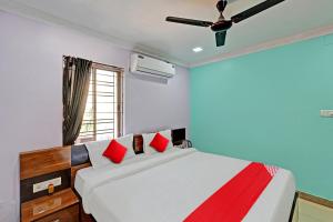 a bedroom with a bed with red pillows and a ceiling fan at OYO Flagship Hi5 Days Inn Premium in Bhubaneshwar