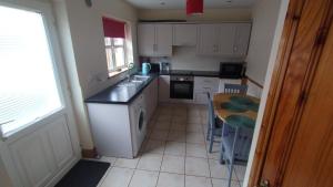 a kitchen with white cabinets and a table and a sink at Townhouse 3 Barrow Lane in Bagenalstown