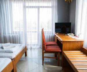 a bedroom with a desk with a chair and a bed at Perła in Leszno