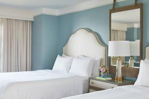 two beds in a hotel room with a mirror at The Grand Hotel Golf Resort & Spa, Autograph Collection in Point Clear