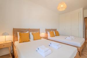 duas camas num quarto com amarelo e branco em Casa de Cotton by MOJE Holiday em Portimão
