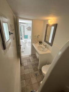 ein Badezimmer mit einem Waschbecken, einem WC und einem Spiegel in der Unterkunft Villa Margarita in Mykonos Stadt