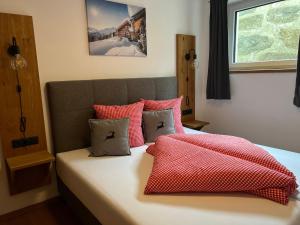 a bedroom with a bed with red and white pillows at Alp Apart Niederthai in Umhausen
