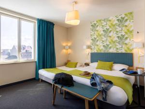 Habitación de hotel con 2 camas y ventana en ibis Styles Calais Centre, en Calais