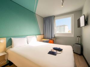 um quarto com uma grande cama branca e uma janela em ibis budget Berlin Kurfürstendamm em Berlim