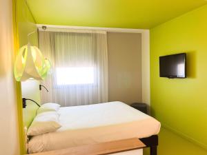 um quarto amarelo com uma cama e uma televisão em ibis Styles Nimes Gare Centre em Nîmes
