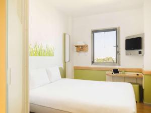 sypialnia z białym łóżkiem i oknem w obiekcie Ibis Budget Sevilla Aeropuerto w Sewilli
