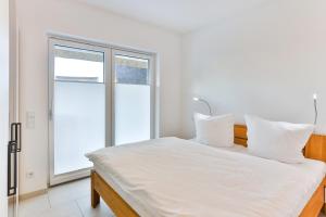 - une chambre blanche avec un grand lit et une fenêtre dans l'établissement Landhaus Wreechen mit Sauna, à Putbus