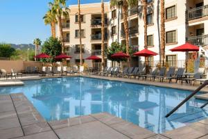 uma piscina num hotel com cadeiras e guarda-sóis em Embassy Suites La Quinta Hotel & Spa em La Quinta