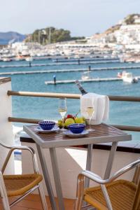 een tafel met een glas wijn en fruit op een balkon bij Hotel Spa Cap de Creus in Port de la Selva