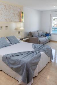 een slaapkamer met een groot bed en een bank bij Hotel Spa Cap de Creus in Port de la Selva