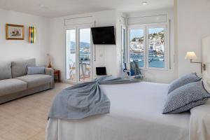 a bedroom with a large white bed and a couch at Hotel Spa Cap de Creus in Port de la Selva