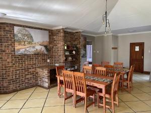 a dining room with a table and chairs and a brick wall at Walkersons Trout and Nature Haven in Dullstroom