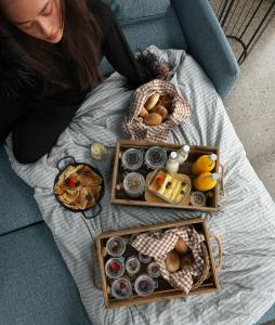 Una donna seduta su un divano con un vassoio di cibo di Wergelandshaugen a Eidsvoll
