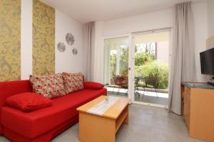 a living room with a red couch and a sliding glass door at Villas Corinthia in Baška
