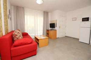 a living room with a red chair and a television at Villas Corinthia in Baška