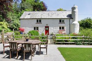 a table and chairs in front of a cottage at Cascade Cottage in Exford