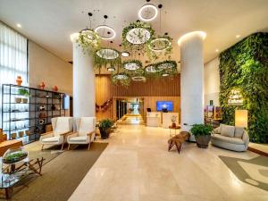 a lobby with white chairs and plants at Grand Mercure SP Itaim Bibi in Sao Paulo