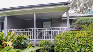 a house with a white porch with bushes at Plover Executive Deluxe Villa 25 in Cams Wharf
